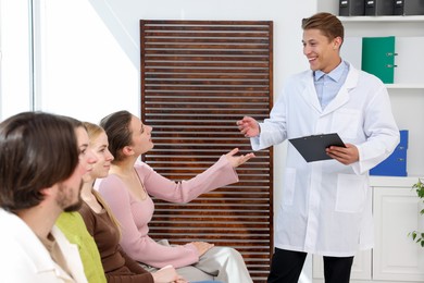 Photo of People waiting in queue on chairs at hospital