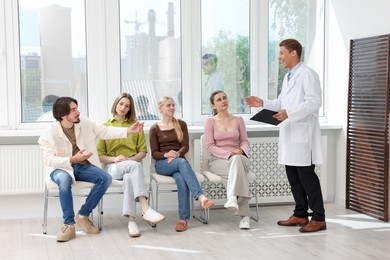 Photo of People waiting in queue on chairs at hospital