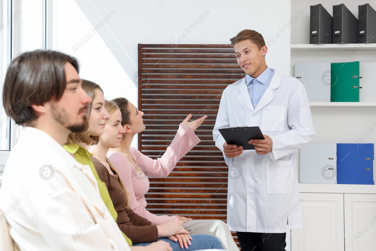 People waiting in queue on chairs at hospital Photo of People waiting in queue on chairs at hospital