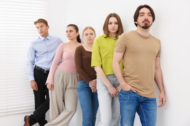 Photo of People waiting in queue near white wall indoors