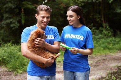 Photo of Volunteers with cute stray dog and toy outdoors. Animal rescue