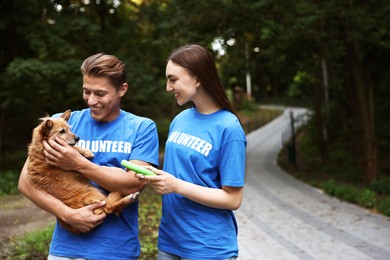 Photo of Volunteers with cute stray dog and toy outdoors, space for text