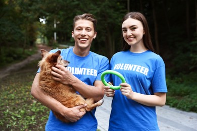 Photo of Volunteers with cute stray dog and toy outdoors