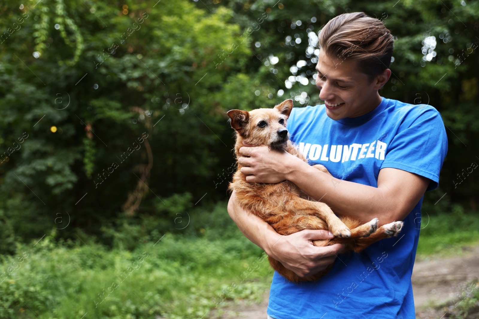 Photo of Volunteer with cute stray dog outdoors, space for text