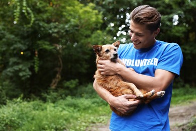 Photo of Volunteer with cute stray dog outdoors, space for text