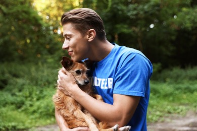 Photo of Volunteer with cute stray dog outdoors. Animal rescue