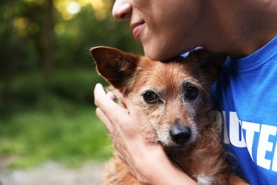 Photo of Volunteer with cute stray dog outdoors, closeup. Space for text