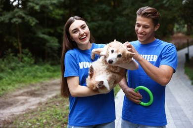 Photo of Happy volunteers with cute stray dog outdoors