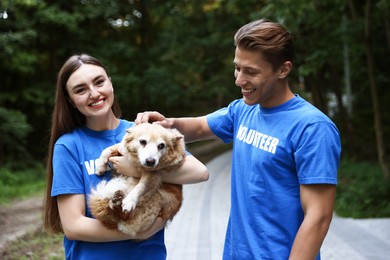 Photo of Happy volunteers with cute stray dog outdoors