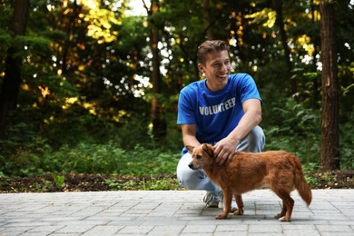 Photo of Volunteer with cute stray dog outdoors, space for text