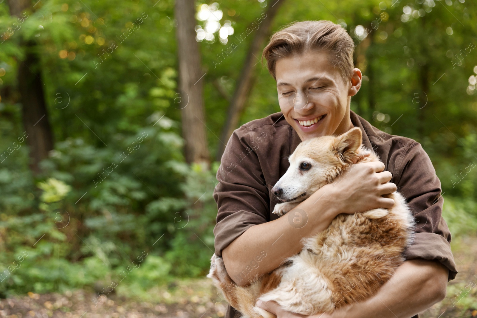 Photo of Happy man holding his cute dog outdoors, space for text