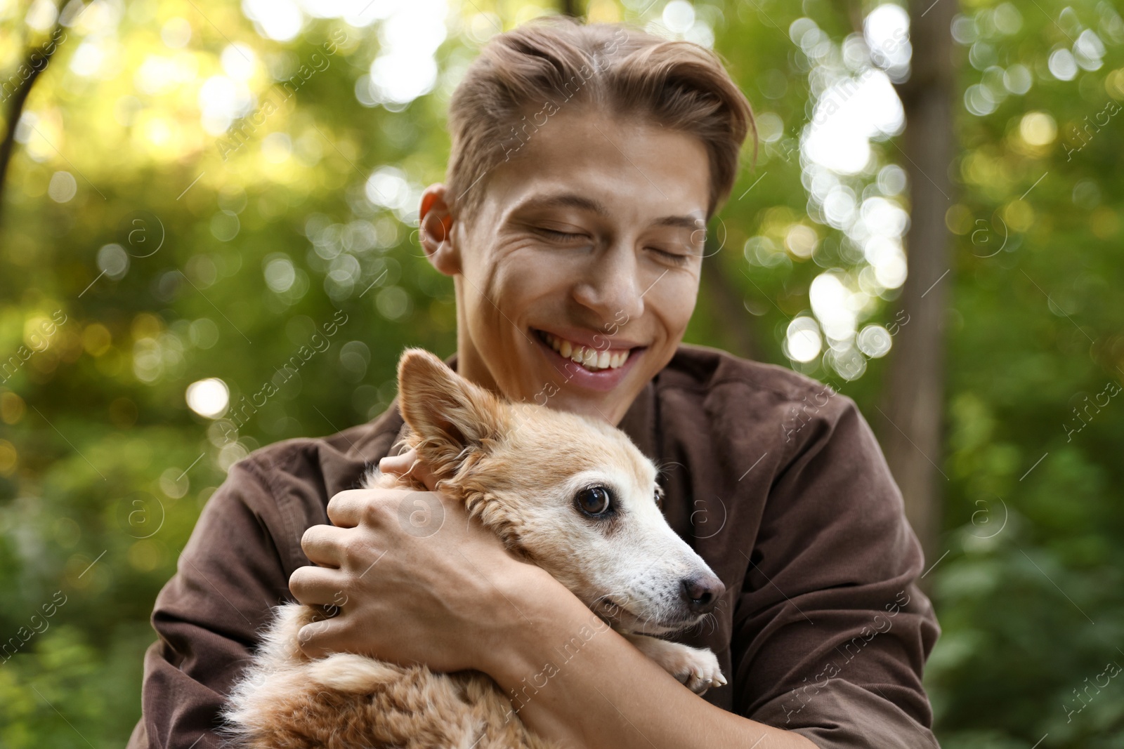 Photo of Happy man holding his cute dog outdoors