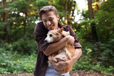 Photo of Happy man holding his cute dog outdoors