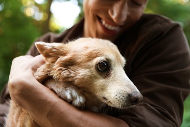 Photo of Man holding his cute dog outdoors, closeup