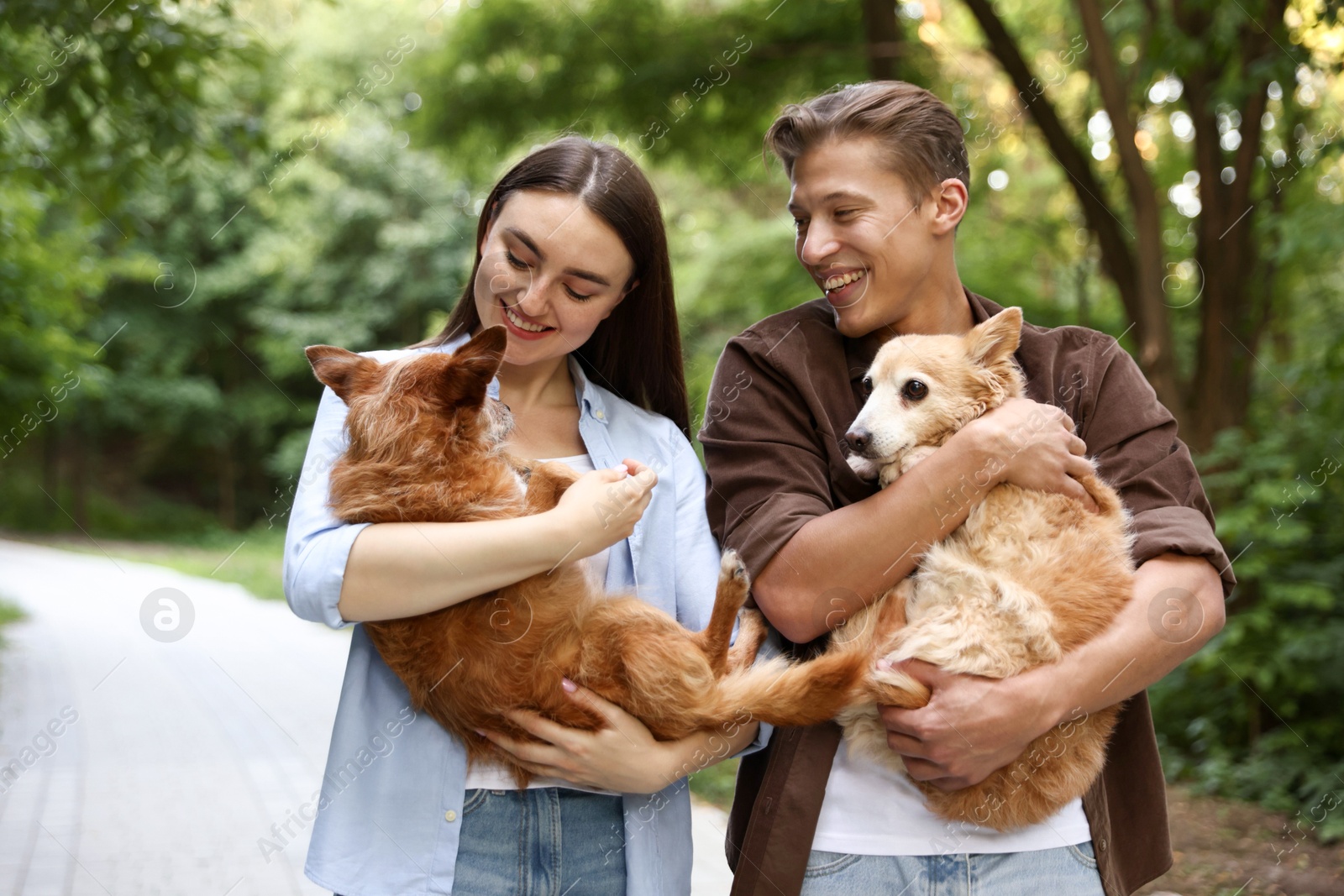 Photo of Happy couple holding their cute dogs outdoors