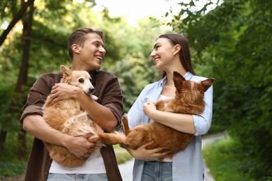 Photo of Happy couple holding their cute dogs outdoors
