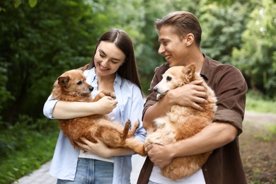 Photo of Happy couple holding their cute dogs outdoors