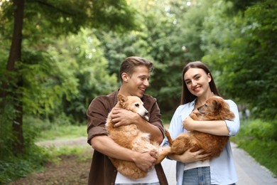 Photo of Happy couple holding their cute dogs outdoors, space for text