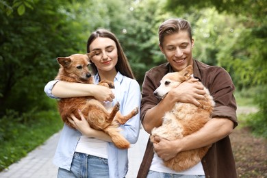 Photo of Happy couple holding their cute dogs outdoors