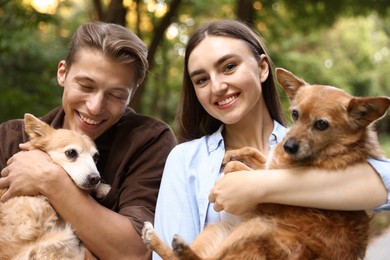 Photo of Happy couple holding their cute dogs outdoors