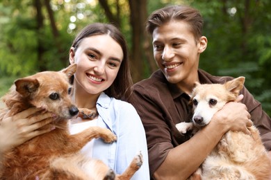 Photo of Happy couple holding their cute dogs outdoors