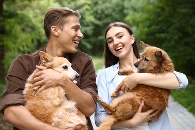 Photo of Happy couple holding their cute dogs outdoors