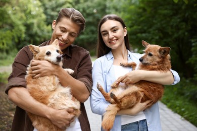 Photo of Happy couple holding their cute dogs outdoors