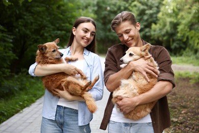 Photo of Happy couple holding their cute dogs outdoors