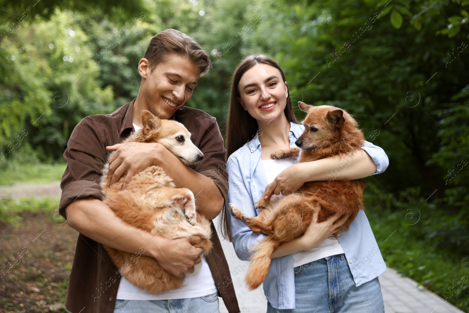 Photo of Happy couple holding their cute dogs outdoors