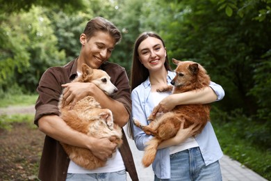 Photo of Happy couple holding their cute dogs outdoors