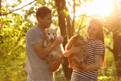 Photo of Happy couple holding their cute dogs outdoors