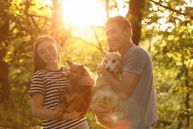 Photo of Happy couple holding their cute dogs outdoors