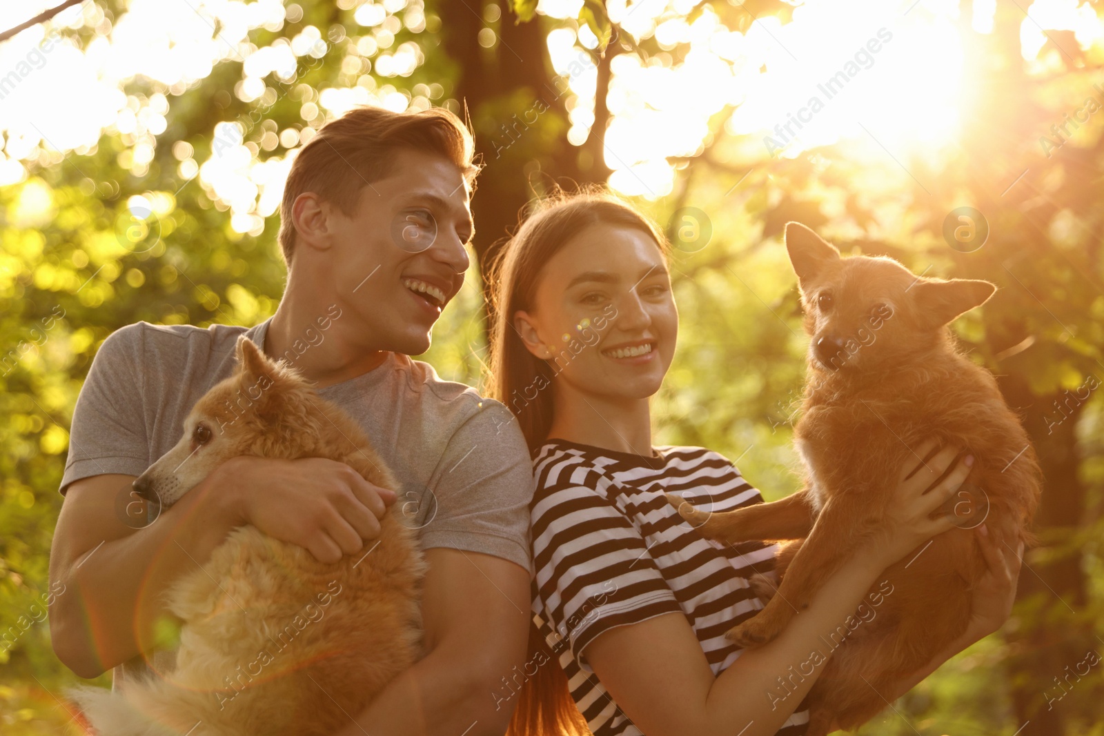 Photo of Happy couple holding their cute dogs outdoors
