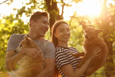 Photo of Happy couple holding their cute dogs outdoors