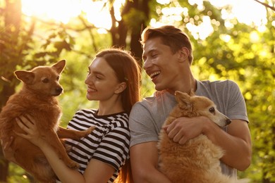 Photo of Happy couple holding their cute dogs outdoors