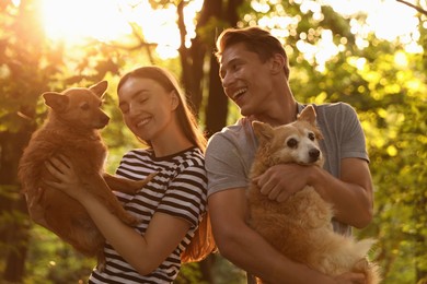Photo of Happy couple holding their cute dogs outdoors