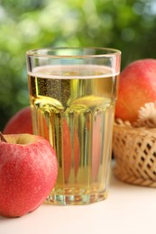 Photo of Delicious cider in glass and apples on white wooden table outdoors, closeup