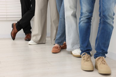 Photo of People waiting in queue near light wall indoors, closeup