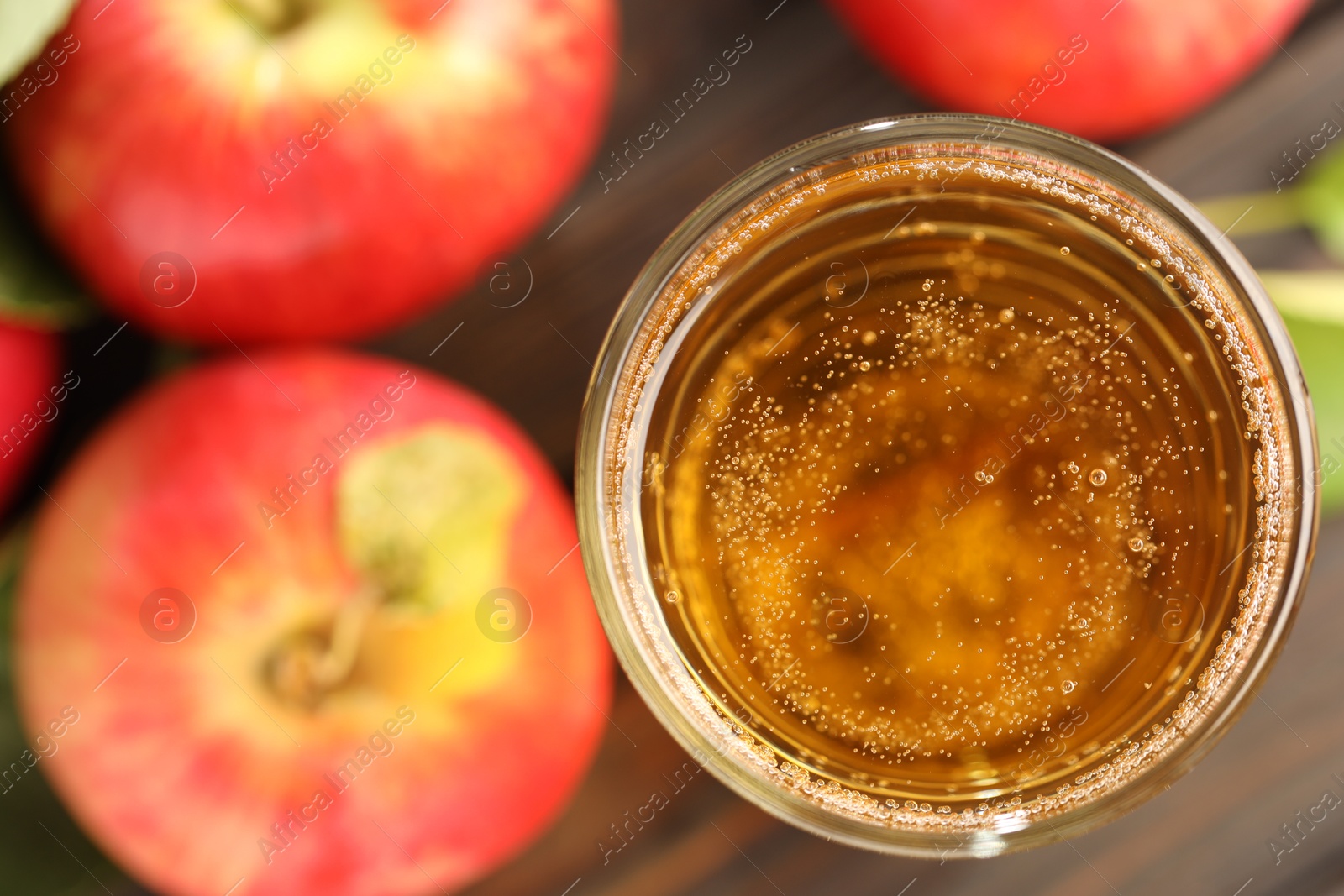 Delicious cider in glass and apples on table, flat lay Photo of Delicious cider in glass and apples on table, flat lay