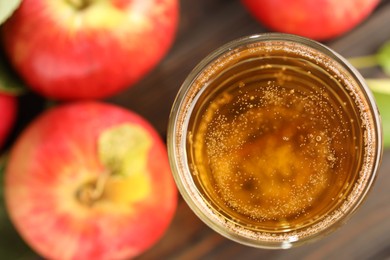 Photo of Delicious cider in glass and apples on table, flat lay