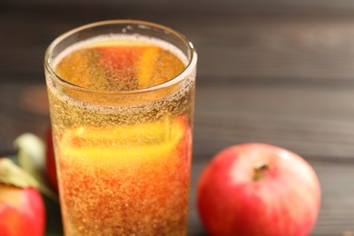 Photo of Delicious cider in glass and apples on table, closeup