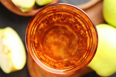 Photo of Delicious cider in glass and apples on table, flat lay
