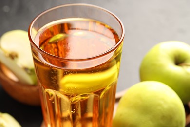 Photo of Delicious cider in glass and apples on table, closeup