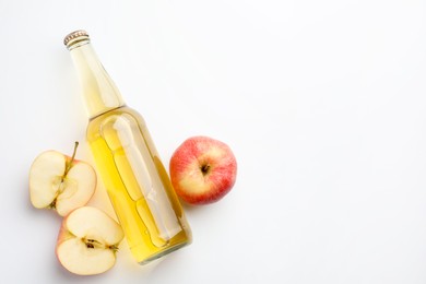 Photo of Delicious cider in glass bottle and apples on white background, flat lay. Space for text