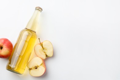 Photo of Delicious cider in glass bottle and apples on white background, flat lay. Space for text