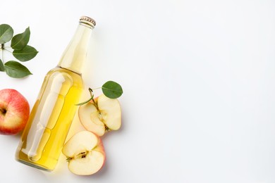 Photo of Delicious cider in glass bottle, apples and green leaves on white background, flat lay. Space for text