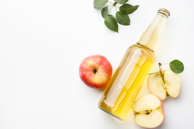 Photo of Delicious cider in glass bottle, apples and green leaves on white background, flat lay. Space for text