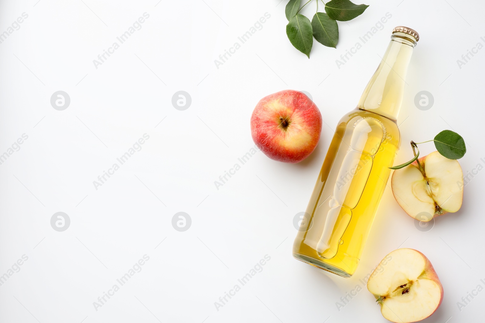 Photo of Delicious cider in glass bottle, apples and green leaves on white background, flat lay. Space for text