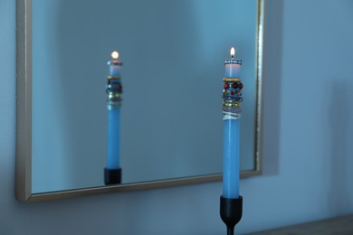 Photo of Burning candle with different rings in front of mirror