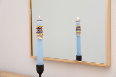Photo of Burning candle with different rings in front of mirror